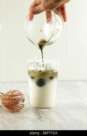 Il tè Matcha viene versato nel latte freddo. Sana bevanda vegana Matcha latte Foto Stock