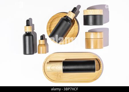 Set di prodotti cosmetici in confezione nera e vetro di bambù. Olio di bellezza in bottiglia contagocce e vasetti con crema per una pelle sana. Confezione senza marchio per c Foto Stock