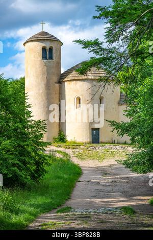 La rotonda di San Giorgio sorge graziosamente sul monte Rip in Cechia, circondata da una vegetazione lussureggiante. Questa struttura storica presenta caratteristiche architettoniche uniche su uno sfondo sereno. Foto Stock
