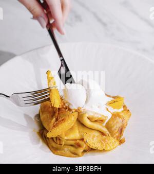 Cibo, deliziosi pancake, cucchiaio di gelato con scorza d'arancia, forchetta in azione Foto Stock
