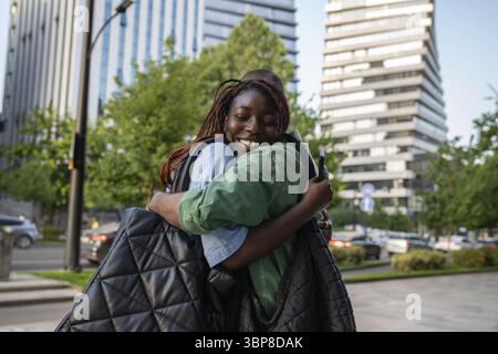 Gioioso incontro di ragazze e amici afroamericani all'aperto. Felici studenti di coppia nera contenti con un buon umore sorridente abbracciando vedendo ogni othe Foto Stock