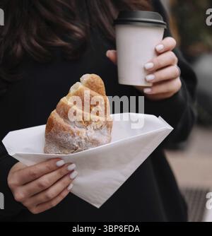 Cibo, primo piano di una donna che assaggia una deliziosa pasticceria e un caffè caldo in un ambiente accogliente all'aperto Foto Stock
