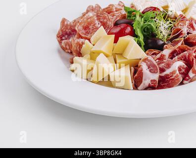 Cibo, salumi assortiti e cubetti di formaggio presentati elegantemente su un piatto bianco Foto Stock