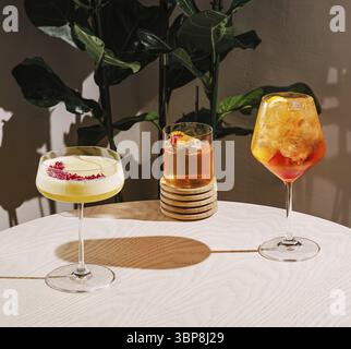 Cibo, tre cocktail colorati sono splendidamente disposti su un tavolo di legno chiaro. Le piante verdi creano un'atmosfera vibrante mentre le bevande mettono in mostra l'uniqu Foto Stock
