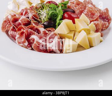 Cibo, salumi assortiti e cubetti di formaggio presentati elegantemente su un piatto bianco Foto Stock