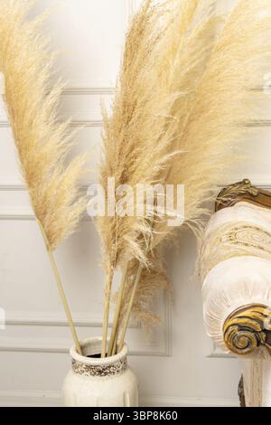 Elegante soggiorno scandinavo interno di un moderno appartamento con pampas erba e un accogliente divano in colori chiari. Un pezzo di divano classico beige e. Foto Stock