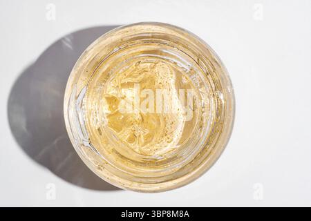 gel crema per la cura della pelle dorata 24 k in un vaso di vetro da primo piano. Prodotto per trattamenti estetici texture macro. Vista dall'alto Foto Stock