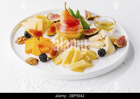 Cibo, elegante disposizione di vari formaggi, fichi freschi, pera e noci su un piatto di ceramica Foto Stock