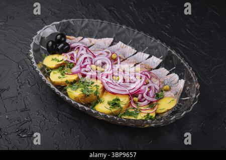 Cibo, aringhe a fette con patate al forno e cipolle marinate su un piatto di vetro Foto Stock