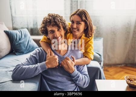 Ritratto di una giovane coppia felice a casa. Guardano la telecamera e sorridono. Foto Stock