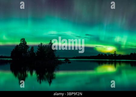 Aurora boreale (nota anche come Aurora Borealis) che si snoda nei cieli a nord di Duluth, Minnesota, riflettendo sulla superficie delle acque calme del lago Boulder Reservoir Foto Stock