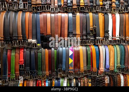 Firenze, Italia - 10 maggio 2025: Cinture in pelle colorata esposte ordinatamente in uno stand del mercato di strada nello storico mercato nuovo Foto Stock