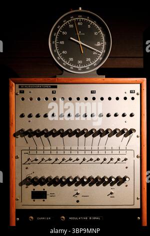 Pannello di controllo retro con interruttori e manopole sotto un orologio analogico con illuminazione soffusa. Foto Stock