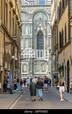 Firenze, Italia - 11 maggio 2025: I turisti camminano lungo una stradina del centro storico, con una splendida vista sul retro della Cattedrale Foto Stock