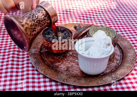 Il tradizionale caffè turco estratto in cezve sulla sabbia viene servito in una piccola tazza di dolci Foto Stock