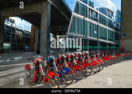 Una fila di biciclette locali è disponibile per il noleggio presso un campus della University Canada West e sotto Granville Street Bridge a Vancouver, British Columbia. Foto Stock