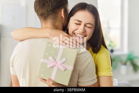 Giovane donna felice che è grata per il presente, abbraccia il suo fidanzato e sorride in generale Foto Stock