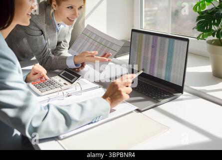 Concentrated businesswomen, female traders looking at laptop screen with stock market data Foto Stock