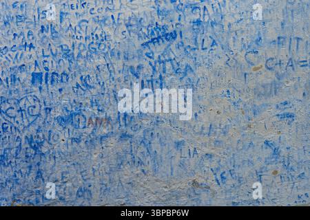Graffiti blu e iscrizioni intemperie su una vecchia parete in gesso, Portogallo. Foto Stock