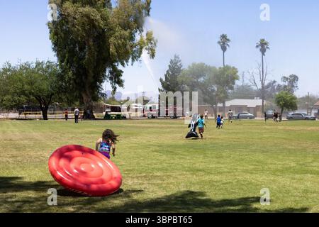 Il camion dei pompieri spruzza acqua sui bambini per divertirsi in estate al Parkview Park di Tucson, Arizona, una pausa fresca sotto il sole del deserto. Foto Stock