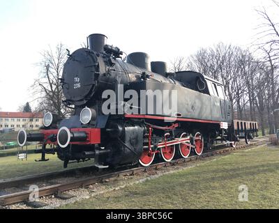 Una locomotiva a vapore polacca d'epoca su un basamento nel parco di Kraków, storico patrimonio industriale incastonato nel verde lussureggiante della città e nell'elegante sfondo urbano Foto Stock