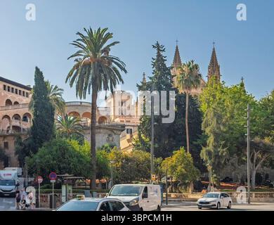 Palma di Maiorca, Spagna - 12 luglio 2024: Palazzo dell'Almudaina e torri della cattedrale viste da Placa de la Reina. Traffico alla rotatoria Foto Stock