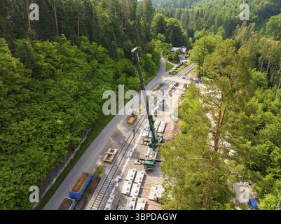 Lavori di costruzione con una gru lungo i binari ferroviari, circondati dalla foresta, costruzione della ferrovia Hermann Hesse, Calw, Germania, Europa Foto Stock