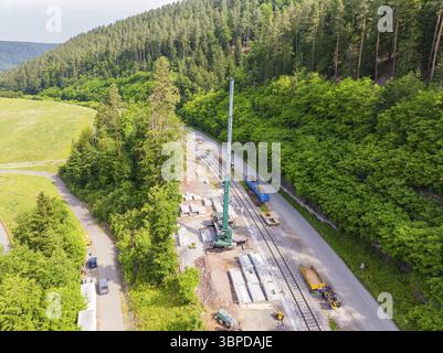 Lavori di costruzione lungo una linea ferroviaria in un'area boschiva verde, gru e blocchi di cemento visibili, costruzione della ferrovia Hermann Hesse, Calw, Ger Foto Stock