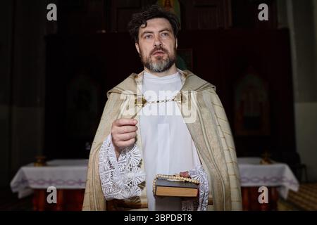 Uomo caucasico di mezza età che svolge rituali religiosi all'interno della Chiesa Foto Stock