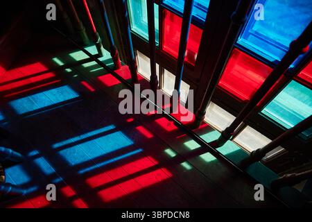 Luce solare colorata che diffonde motivi vivaci attraverso le vetrate colorate Foto Stock