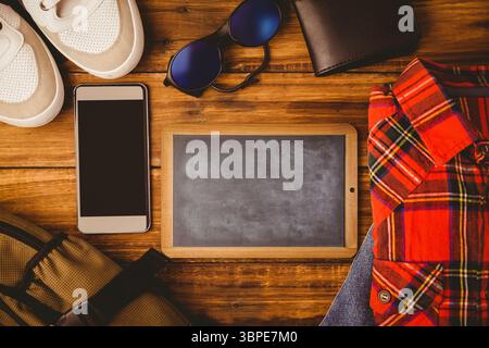 Posate su un tavolo di legno, con lavagna, telefono, scarpe da ginnastica, camicia a quadri e zaino Foto Stock