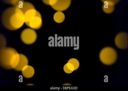 I cerchi gialli dorati fluttuano dolcemente sulla scena scura con un soffice effetto bagliore, ideali per le feste di nozze o per composizioni a tema caldo Foto Stock