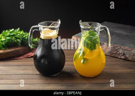 Kvass e limonata in brocche di vetro su un tavolo di legno Foto Stock