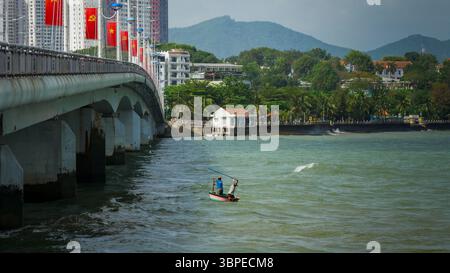 Pescatori tradizionali vietnamiti in una barca a cesto rotondo sotto il ponte Tran Phu, Nha Trang, Vietnam Foto Stock