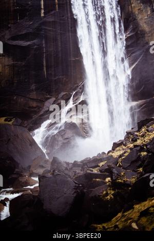 Vista dell'acqua che si getta lungo il terreno roccioso, un potente spettacolo contro la pietra scura, la nebbia che si innalza per incontrare la luce, Yosemite, California, Stati Uniti. Foto Stock