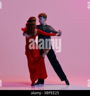 Ballerini eleganti che eseguono un appassionato tango argentino su un vivace sfondo rosa Foto Stock