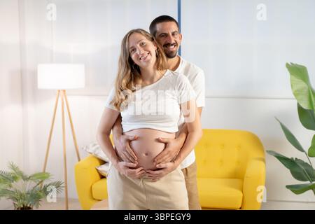 Gravidanza coppia ritratto sorridente felice toccando la pancia Foto Stock