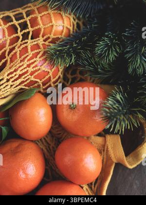 Biglietto d'auguri natalizio mandarini in griglia, giocattoli marroni sull'albero di Natale e nobilis di abete rosso blu nella vista da vicino sulla neve dall'alto Foto Stock