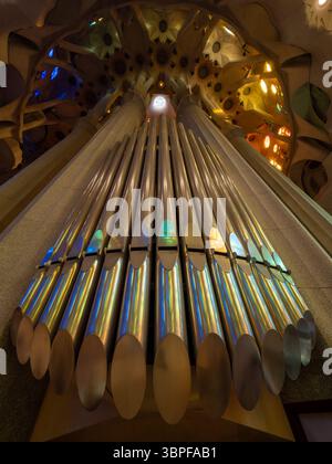 Vista ad angolo basso del magnifico organo a canne, che riflette la luce colorata dalle vetrate della Sagrada Familia, Barcellona, Spagna. Foto Stock