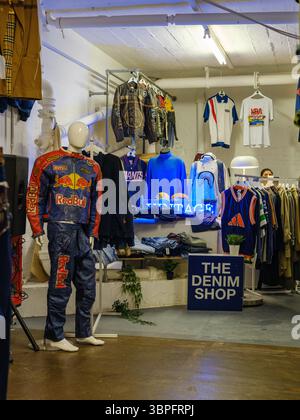 Regno Unito, Londra, 13 luglio 2025. Interno di un negozio di abbigliamento retrò a Shoreditch con tute da corsa Red Bull vintage e abbigliamento in denim Foto Stock