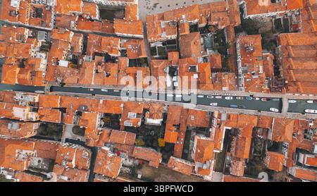 Vista aerea dei tetti in terracotta che si infrangono lungo i tortuosi canali che riflettono il cielo, con barche che ormeggiano dolcemente lungo i corsi d'acqua, Venezia, Italia. Foto Stock