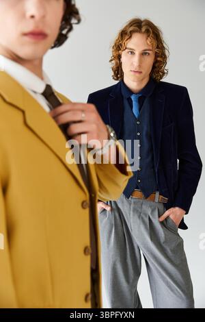 Due giovani uomini alla moda si mettono in posa con fiducia, mettendo in risalto i loro stili unici in un'eleganza informale. Foto Stock