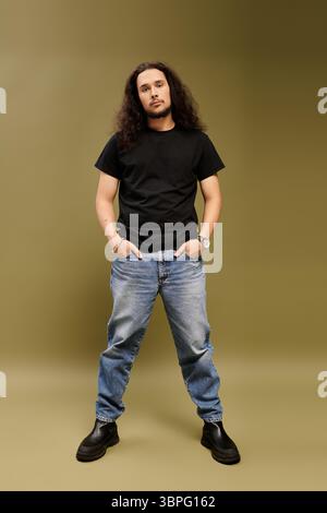 Un giovane uomo barbuto trasuda fascino mentre si posa casualmente in abiti alla moda con un'aria sicura. Foto Stock