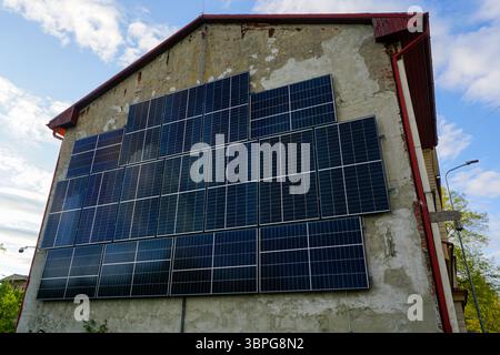 Pannelli solari montati a parete su un vecchio edificio che sfruttano l'energia rinnovabile dal sole del mattino Foto Stock