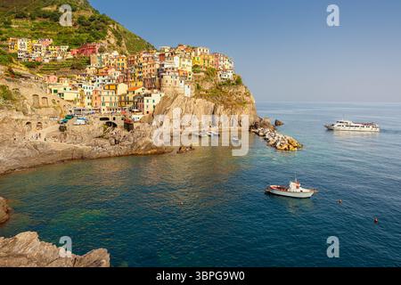 La luce del sole del pomeriggio mette in risalto le colorate case sulla scogliera di Manarola, affacciate sul mare delle cinque Terre Foto Stock