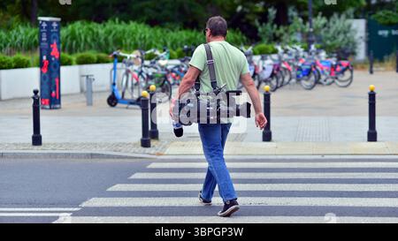 Varsavia, Polonia. 8 luglio 2025. Un cameraman con attrezzatura professionale per girare la strada pedonale. Foto Stock