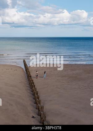Due persone camminano sulla spiaggia sabbiosa di Bridlington UK Foto Stock