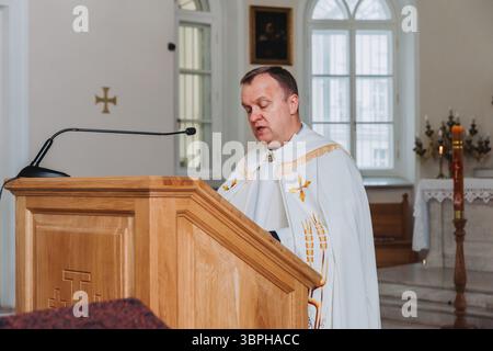 Mosca Russia - 23 dicembre 2024 - sacerdote in abito bianco che tiene un discorso su un altare all'interno di una chiesa luminosa Foto Stock