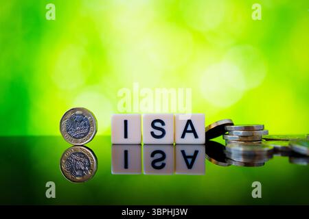 Immagine lucida di cubi ISA con moneta da sterlina verticale e pezzi sparsi in sterline che illustrano opzioni di risparmio e di investimento esentasse nel Regno Unito. Foto Stock