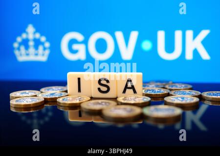 Tessere di lettera ISA con monete in sterline britanniche davanti allo sfondo di GOV.UK che illustra lo schema di risparmio esente da imposte supportato dal governo britannico. Stafford, United K Foto Stock